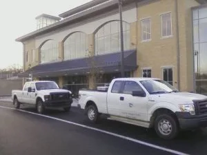 Two city trucks parked outside the train station, with motors idling. Over the years, maintenance and security will also probably turn out to be very costly.